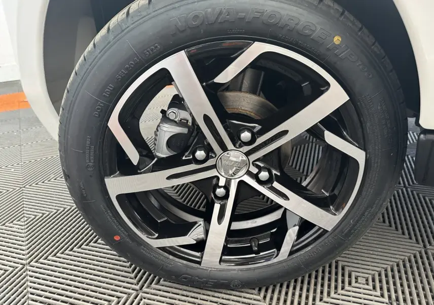 Gros plan sur la roue avant droite de l'AIXAM AMBITION 0.5 CROSSOVER PREMIUM blanche avec jante noire et argentée.