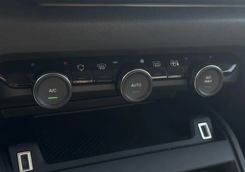 Détail des commandes de climatisation automatique avec boutons rotatifs dans l'habitacle noir du Citroën C4 Hybrid 2025.