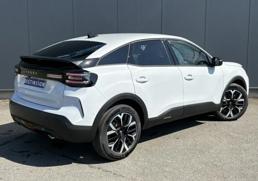 Vue 3/4 arrière droite d'une Citroën C4 Hybrid 145 blanche Okénite avec jantes alliage 18'' et toit noir contrasté.