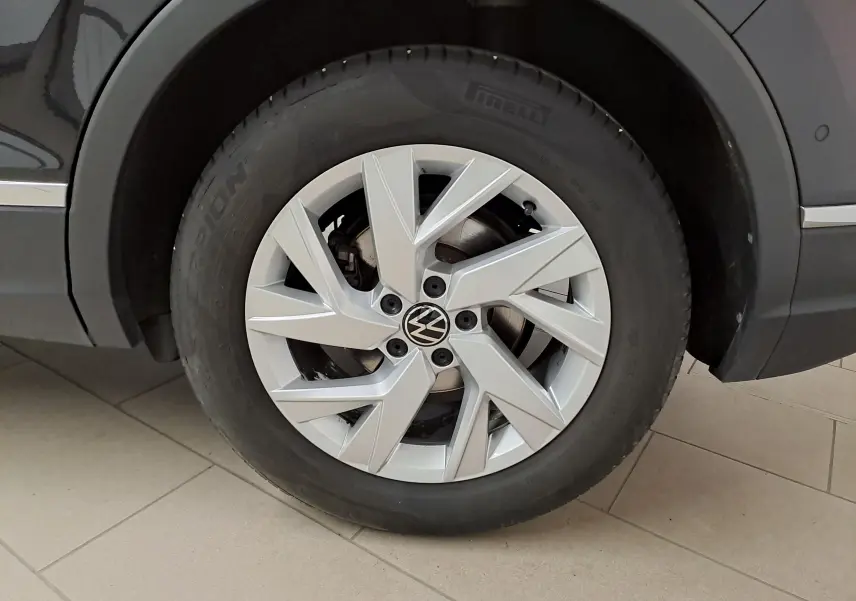 Gros plan sur la roue avant gauche du Volkswagen Tiguan noir intense, mettant en valeur la jante alliage et le pneu Pirelli.