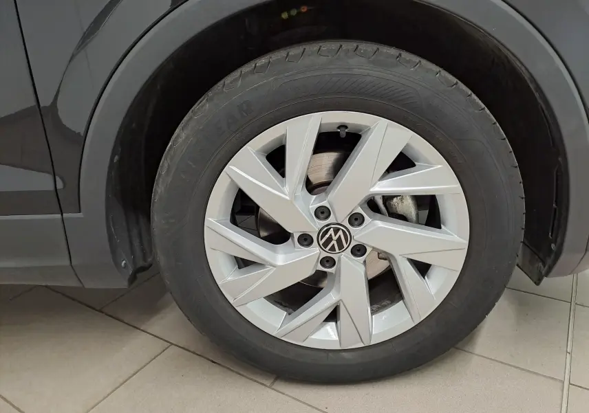 Gros plan sur la roue avant gauche du Volkswagen Tiguan noir intense, mettant en valeur la jante argentée au design moderne.