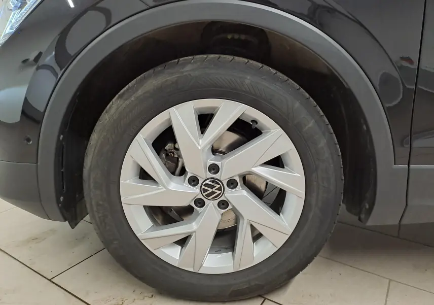 Gros plan sur la roue avant gauche du Volkswagen Tiguan noir intense, mettant en valeur la jante alliage et le pneu Goodyear.