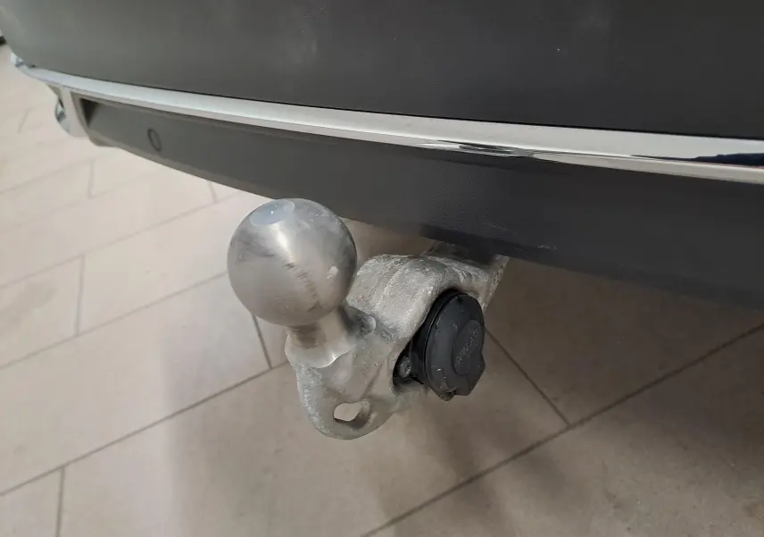 Gros plan sur le crochet d'attelage escamotable en métal fixé sous le pare-chocs arrière noir intense du Volkswagen Tiguan.