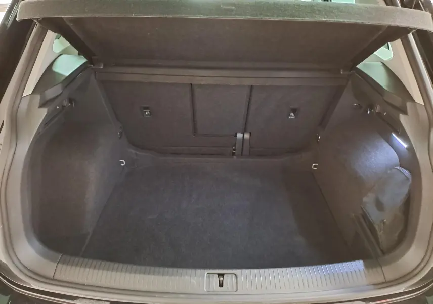 Vue intérieure du coffre ouvert d'un Volkswagen Tiguan noir intense 2022, montrant un espace de rangement propre et spacieux.