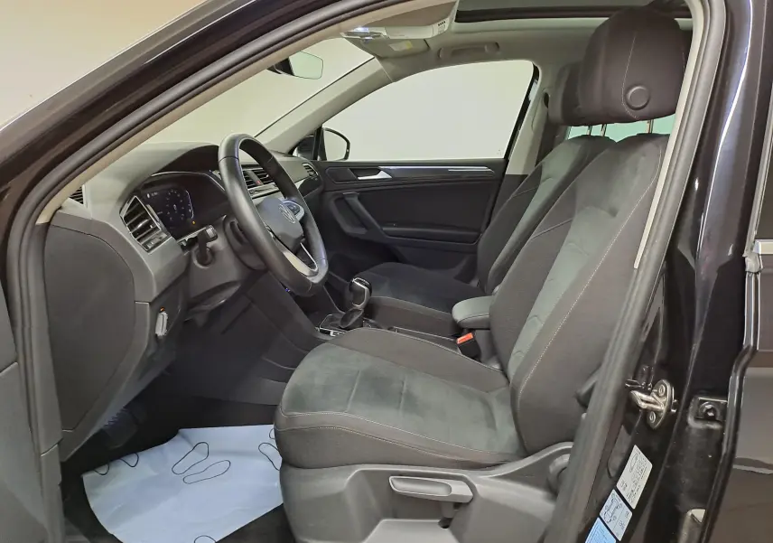 Vue intérieure côté conducteur du Volkswagen Tiguan 2022 noir intense, montrant sièges et tableau de bord épurés.
