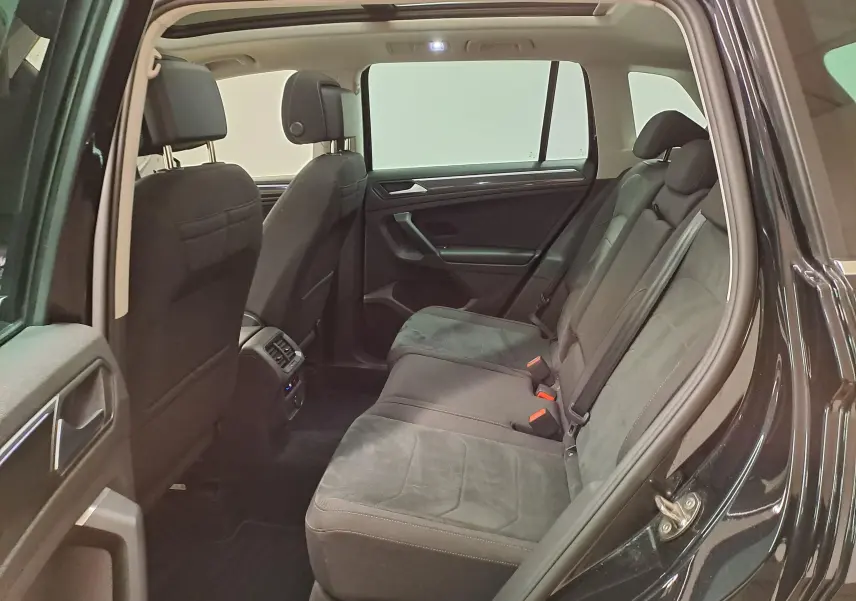 Vue intérieure côté gauche des sièges arrière du Volkswagen Tiguan noir intense 2022, montrant les assises en tissu et alcantara.