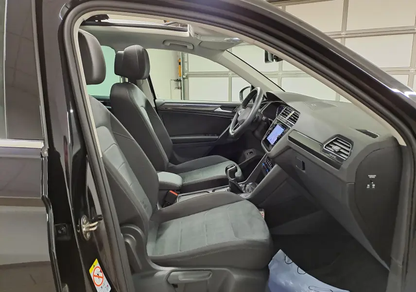 Vue intérieure côté gauche du Volkswagen Tiguan noir intense 2022, montrant les sièges avant et le tableau de bord.