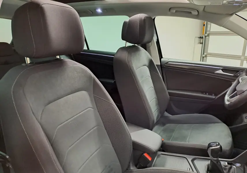 Vue intérieure du Volkswagen Tiguan 2022 montrant les sièges avant en tissu noir et la console centrale avec levier de vitesse.