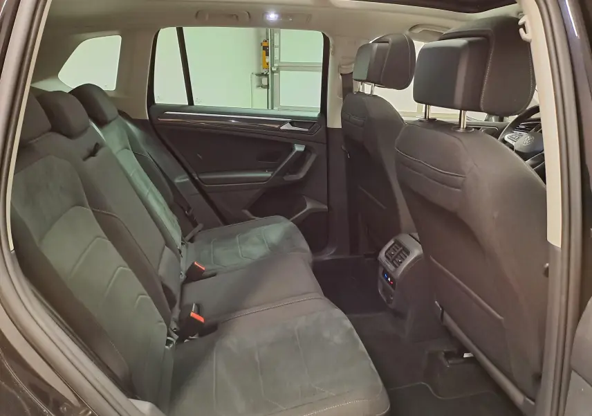 Vue intérieure côté gauche du Volkswagen Tiguan 2022 noir intense, montrant les sièges arrière et la console centrale.