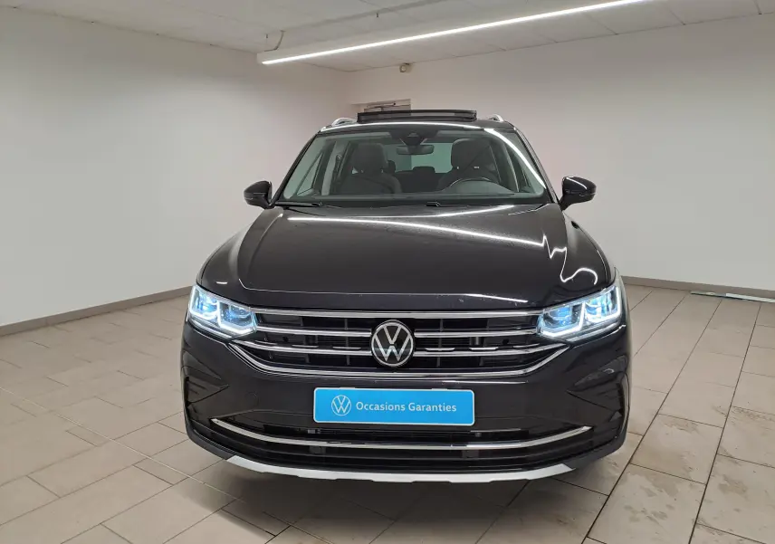 Vue frontale d'un Volkswagen Tiguan noir intense 2022 avec phares allumés et plaque "Occasions Garantis".