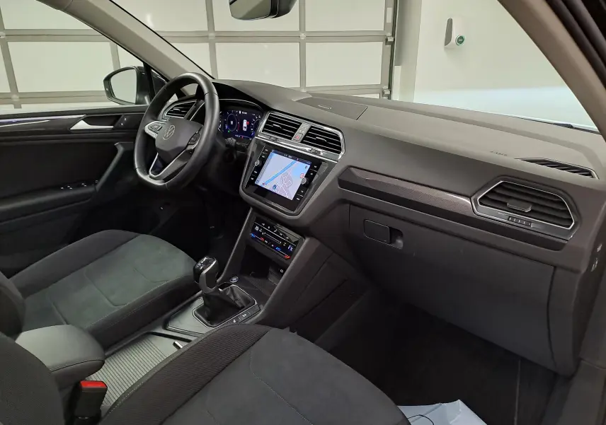 Vue intérieure côté conducteur du Volkswagen Tiguan 2022 avec tableau de bord noir et écran tactile central allumé.