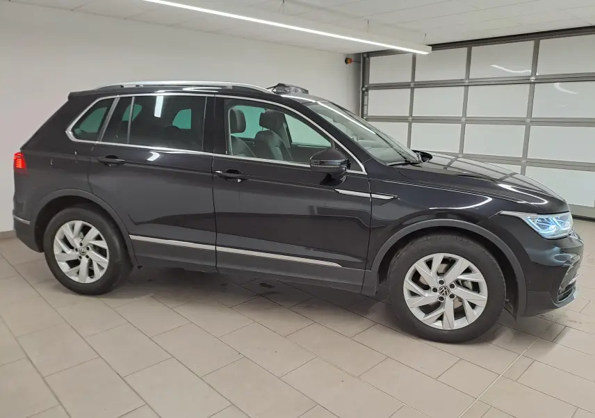 Vue de profil côté gauche du Volkswagen Tiguan 2022 noir intense avec attelage escamotable en garage intérieur.