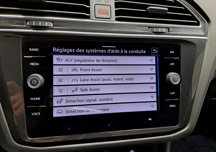 Écran tactile central du Volkswagen Tiguan 2022 affichant les réglages des aides à la conduite, intérieur noir.