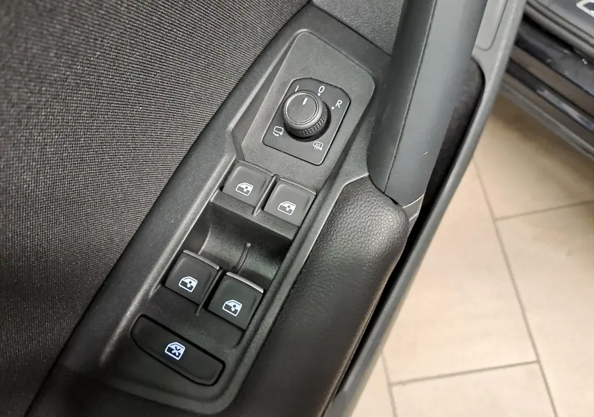 Gros plan sur les commandes de réglage des rétroviseurs et des vitres côté conducteur du Volkswagen Tiguan noir intense 2022.