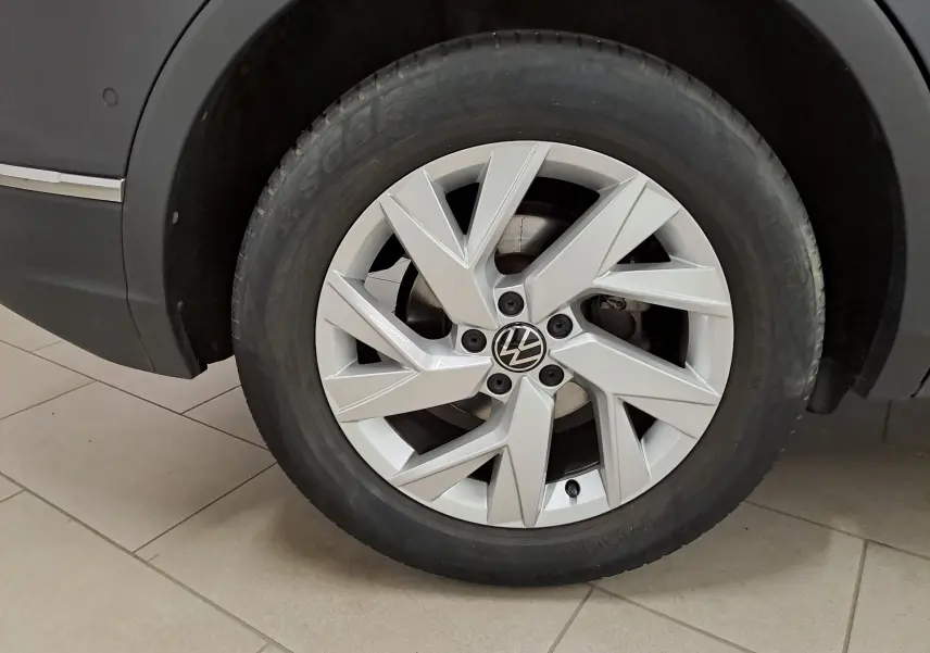 Gros plan sur la roue avant droite du Volkswagen Tiguan noir intense, mettant en valeur la jante alliage au design moderne.