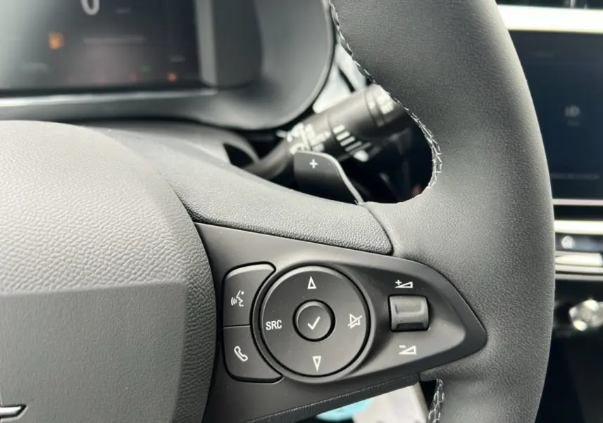 Gros plan sur les commandes multifonctions noires du volant cuir de l’Opel Corsa Hybrid blanc Kontur, version 2026.