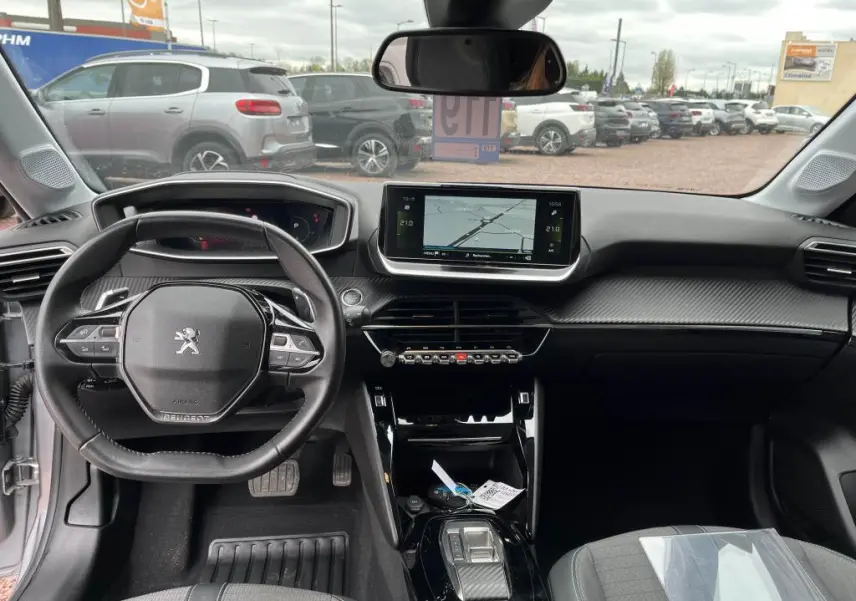 Vue intérieure avant de la Peugeot 208 gris clair 2022, avec tableau de bord moderne et écran tactile central 7 pouces.