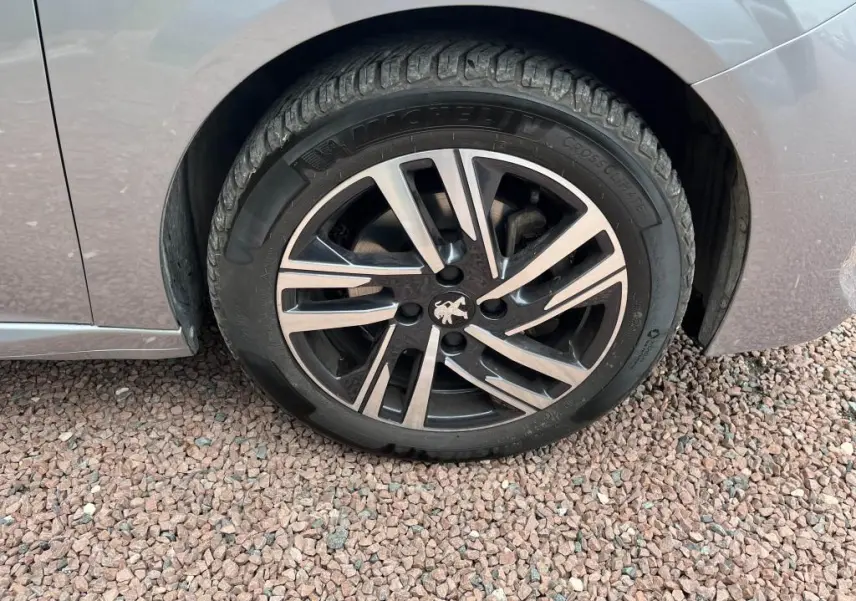 Gros plan sur la roue avant gauche gris clair d'une Peugeot 208 2022 avec jante alliage et pneu Michelin.