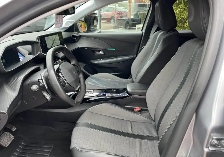 Intérieur avant gris clair de la Peugeot 208 2022, vue côté conducteur avec volant compact et écran tactile central.