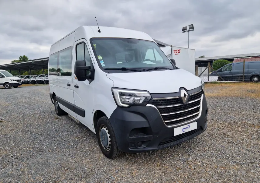 Renault Master blanc en 3/4 avant droit, utilitaire avec large pare-chocs noir et grandes vitres latérales.