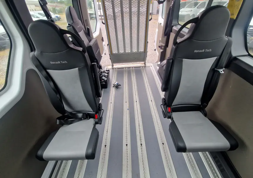 Vue intérieure arrière du Renault Master blanc, montrant deux sièges Renault Tech et une rampe d'accès déployée.