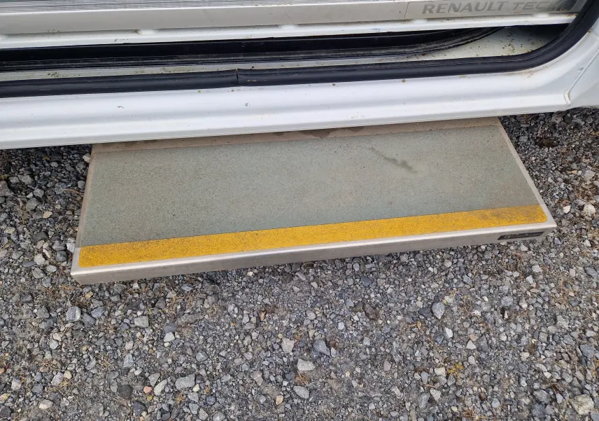 Marchepied latéral gris avec bande jaune sur Renault Master blanc, vue rapprochée de la porte ouverte côté droit.