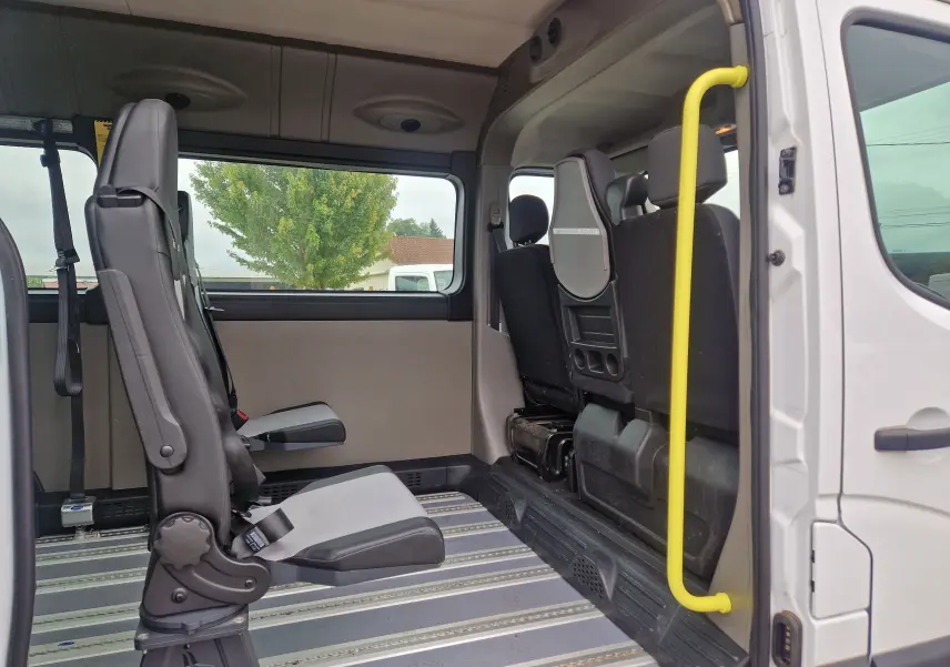 Vue intérieure côté droit du Renault Master blanc 2020 TPMR, montrant les sièges passagers et la barre d’appui jaune.