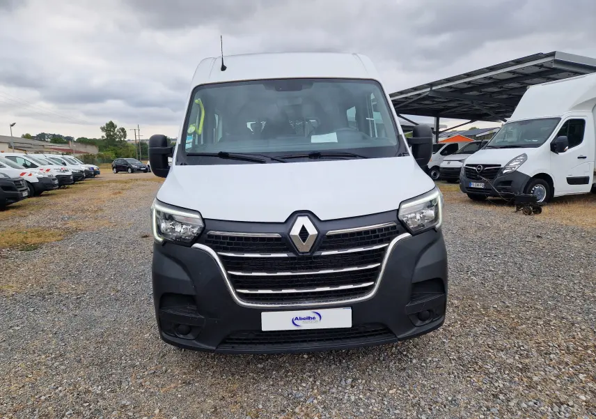 Vue de face d’un Renault Master blanc avec calandre noire et logo chromé, stationné sur un sol gravillonné.