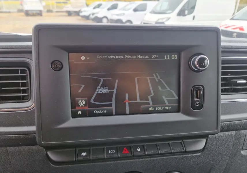 Gros plan sur l'écran tactile du tableau de bord du Renault Master blanc, affichant un GPS avec carte et options radio.