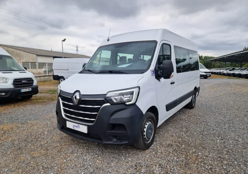 Renault Master blanc en 3/4 avant droit, minibus TPMR avec rampe arrière et marchepied latéral visible.