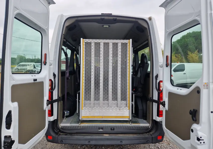 Vue arrière du Renault Master blanc 2020 avec portes ouvertes, montrant la rampe arrière métallique pour fauteuil roulant.
