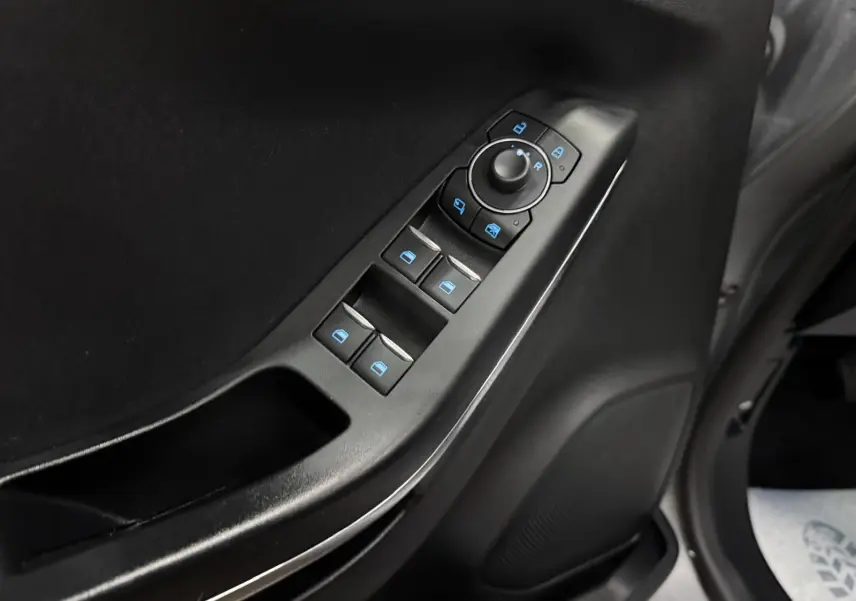 Gros plan sur les commandes de lève-vitres et rétroviseurs côté conducteur du Ford Puma gris Solar 2023.