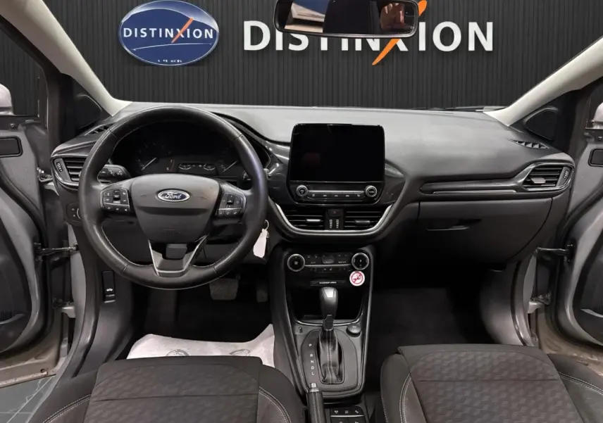 Vue intérieure frontale du tableau de bord et volant du Ford Puma gris Solar, avec écran tactile et boîte automatique visible.