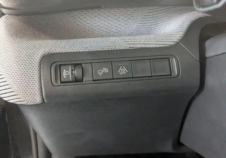 Gros plan sur les commandes de réglage des phares et aides à la conduite dans l’habitacle du Citroën E-C3 Aircross noir 2025.