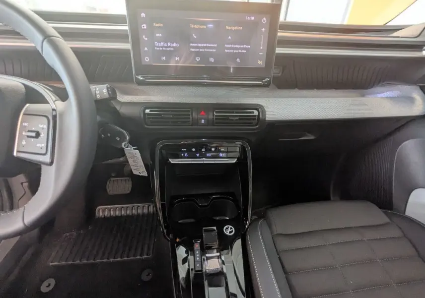 Vue intérieure centrée sur la console et le tableau de bord noir du Citroën E-C3 Aircross 2025 avec écran tactile et sellerie TEP/tissu.