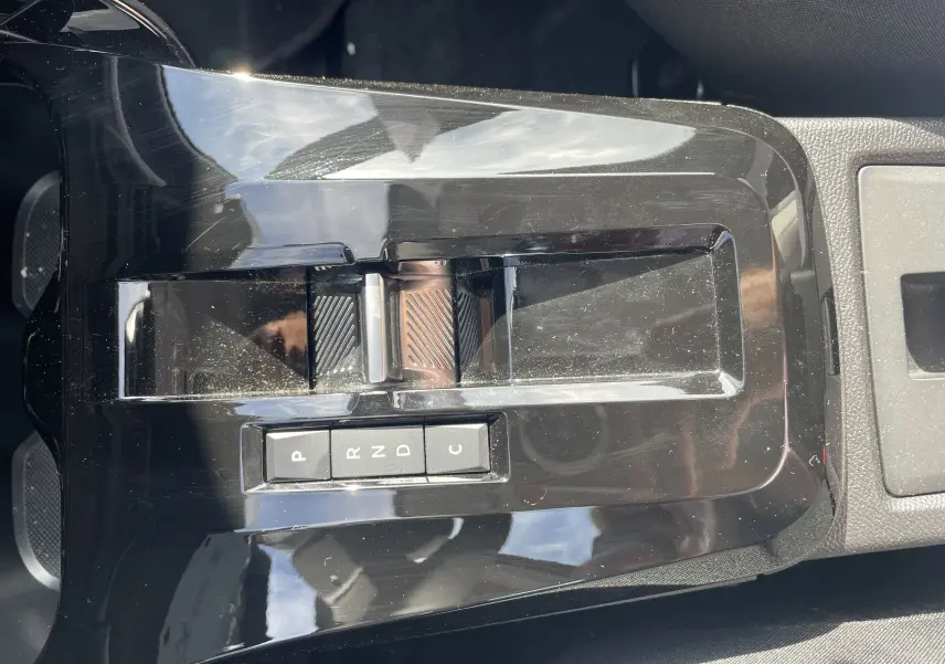 Gros plan sur la console centrale noire brillante du Citroën E-C3 Aircross 2025 avec levier de vitesses automatique et boutons P, R, N, D, C.