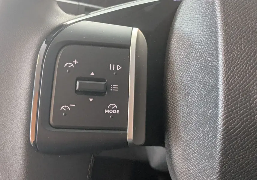Gros plan sur les commandes au volant du Citroën E-C3 Aircross 2025, avec finition noire et boutons de régulateur de vitesse.