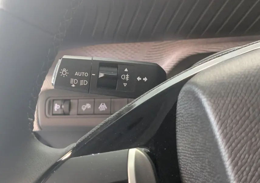 Gros plan sur la commande des feux automatiques et clignotants côté gauche du volant d’une Citroën C3 Aircross noire.