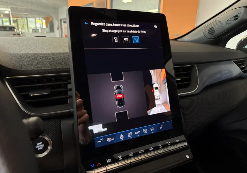 Vue intérieure du tableau de bord du Renault Symbioz gris cassiopée, écran tactile affichant l'aide au stationnement avec vue 360°.