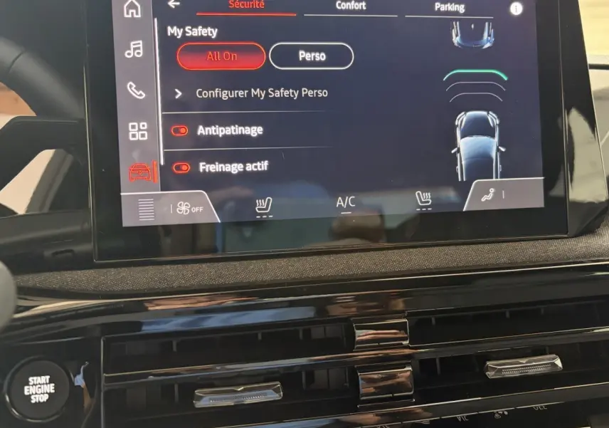 Vue rapprochée de l’écran tactile central de la Renault Clio rouge 2025, affichant les réglages de sécurité et confort.