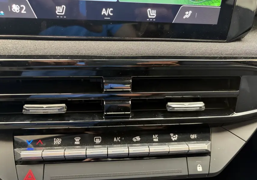 Détail de la console centrale de la Renault Clio 2025 rouge, montrant les commandes de climatisation et les aérateurs noirs.