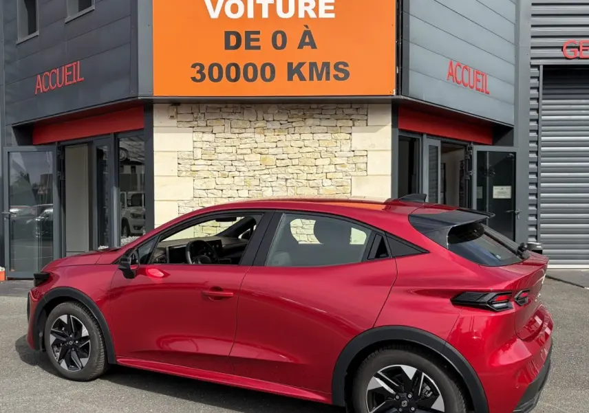 Renault Clio Evolution rouge vue de profil côté gauche, avec jantes noires et toit légèrement incliné.