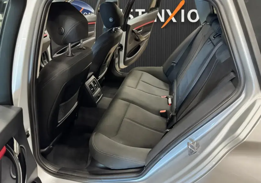 Vue intérieure côté gauche montrant la banquette arrière noire et la portière ouverte d'une BMW Série 3 Touring gris aluminium.
