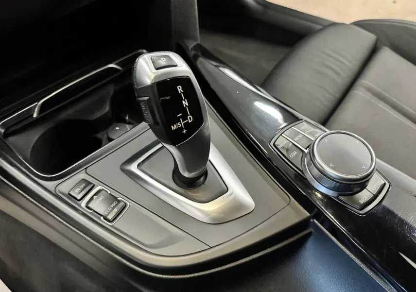 Gros plan sur la console centrale noire de la BMW Série 3 Touring F31 avec levier de vitesse automatique et molette de commande.