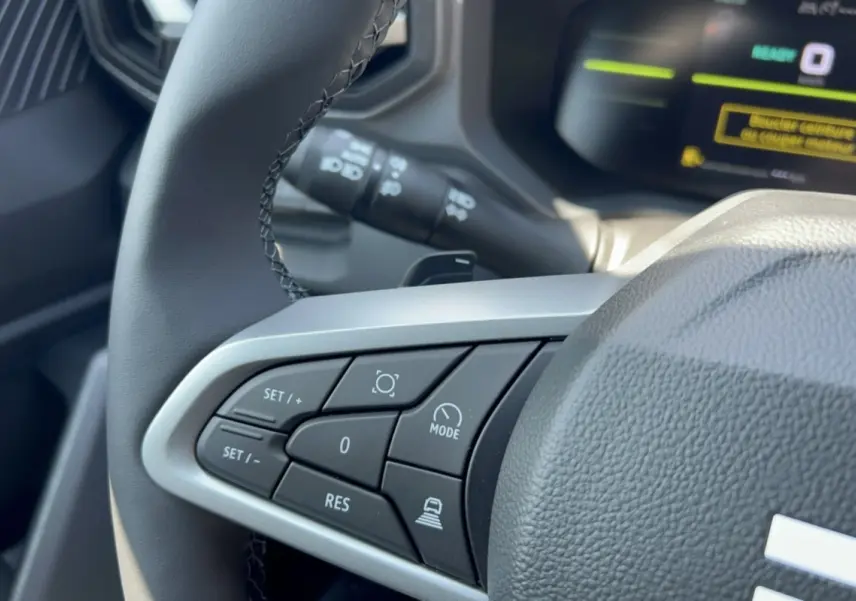 Gros plan sur les commandes de régulateur de vitesse au volant cuir du Dacia Duster Hybrid-G 150 4x4.