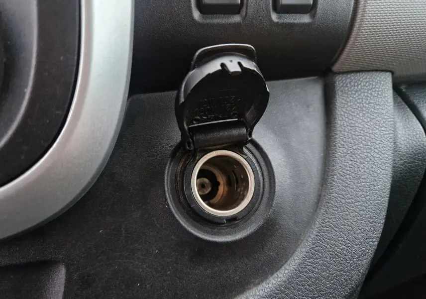 Prise allume-cigare ouverte sur le tableau de bord noir du Renault Trafic Fourgon blanc, version L1H1 2019.