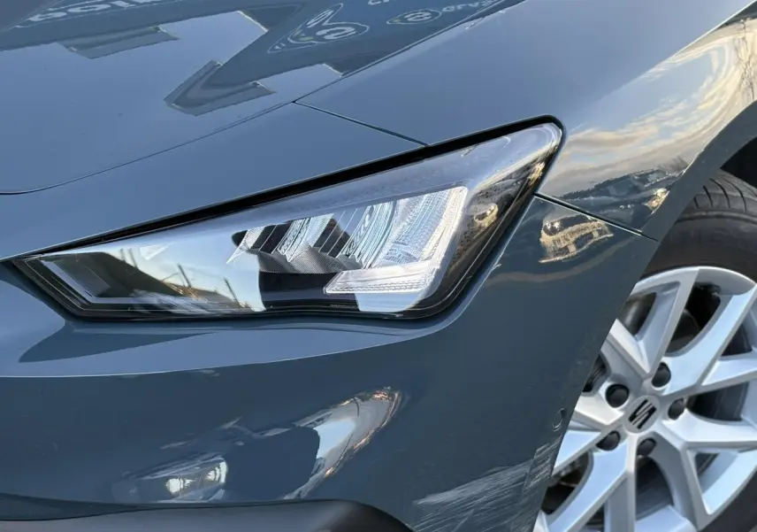 Gros plan sur le projecteur avant gauche et la jante alliage 16 pouces d'une SEAT LEON ST Bleu Fjord 2025.