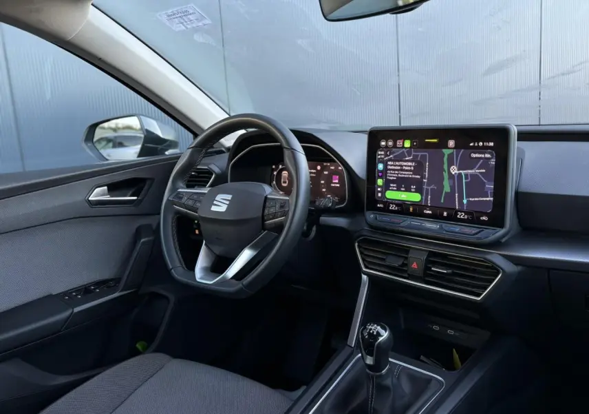 Vue intérieure côté conducteur du SEAT LEON ST 2.0 TDI 115 Style 2025, volant cuir multifonction et écran tactile central.