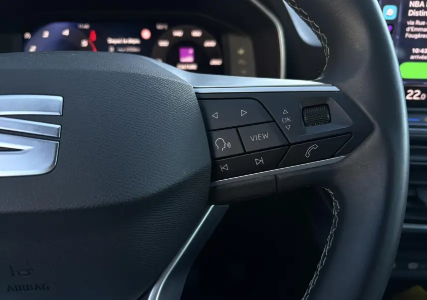 Gros plan sur le volant cuir multifonction côté droit du SEAT LEON ST Bleu Fjord avec commandes intégrées.