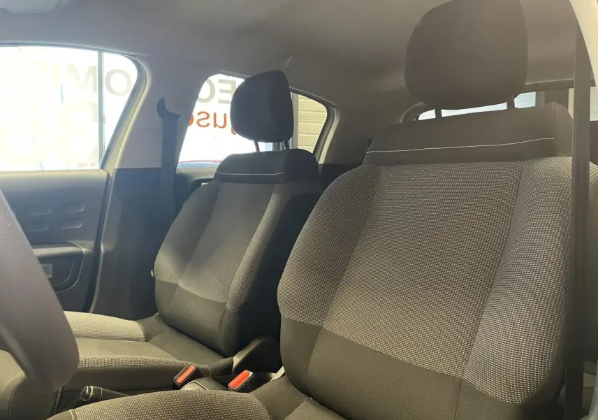 Vue intérieure des sièges avant en tissu gris avec surpiqûres jaunes de la Citroën C3 2024 beige clair.